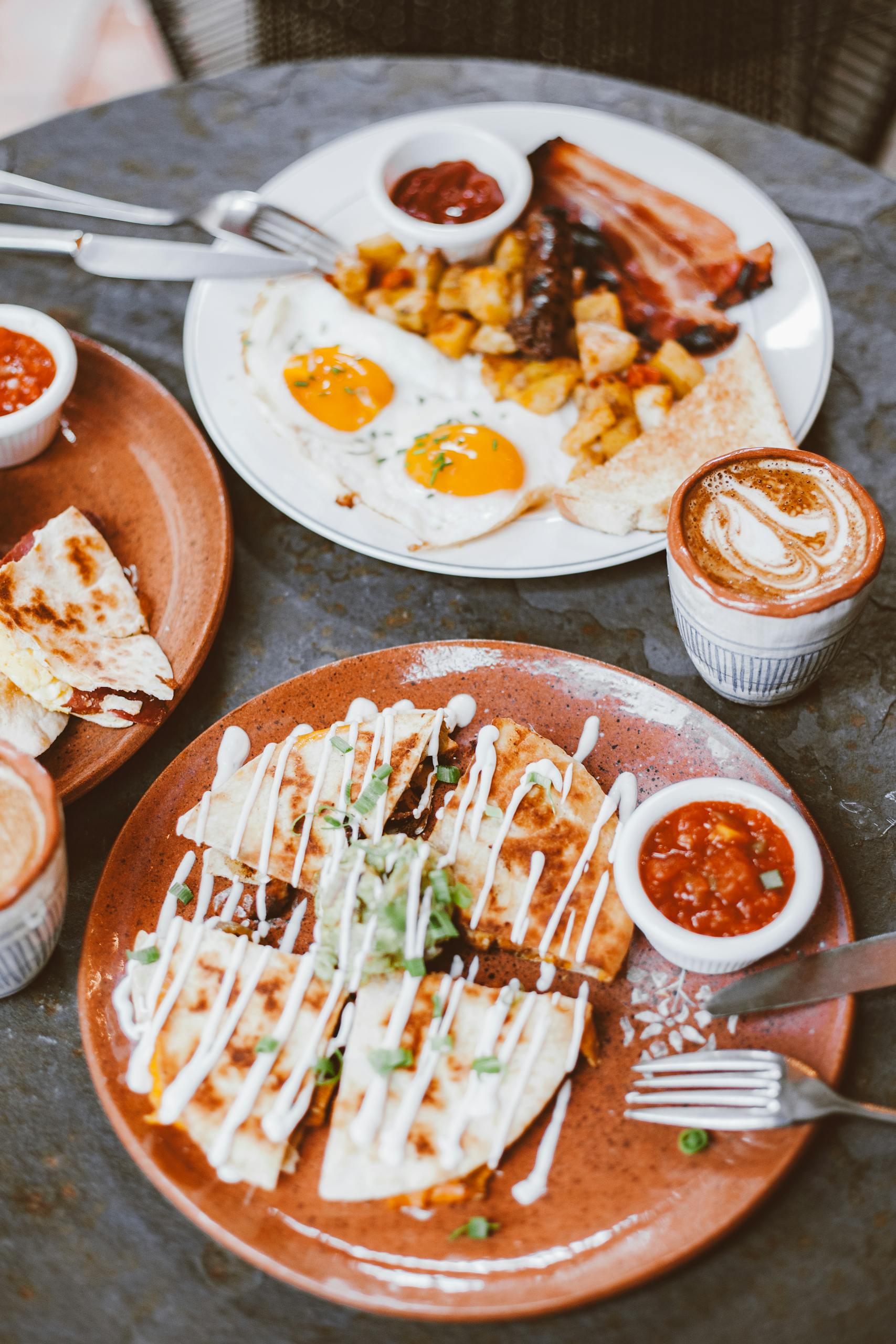 Delicious breakfast featuring sunny-side-up eggs, bacon, and quesadillas with salsa.